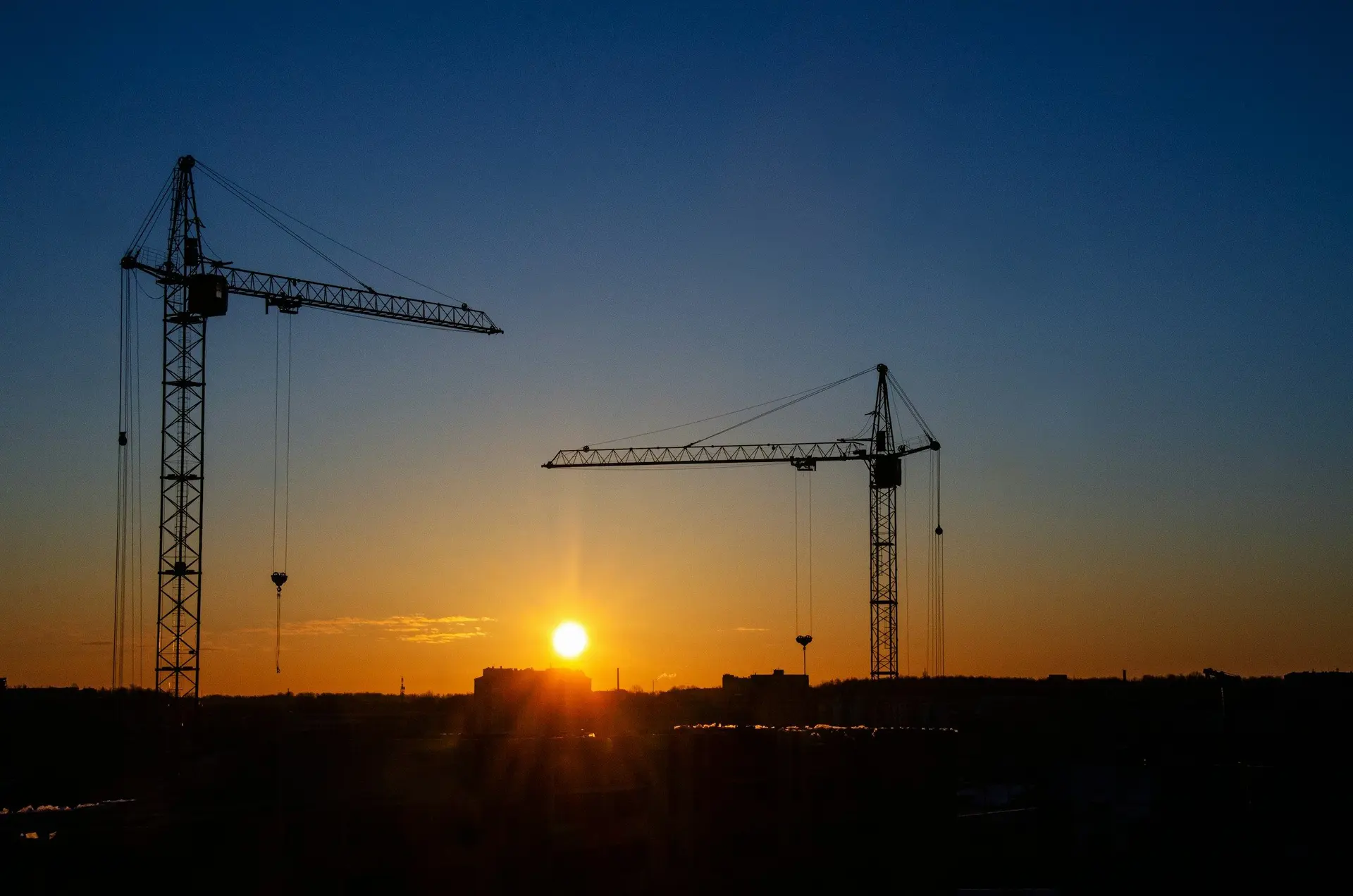 Silhouettes de grues de chantier au coucher du soleil